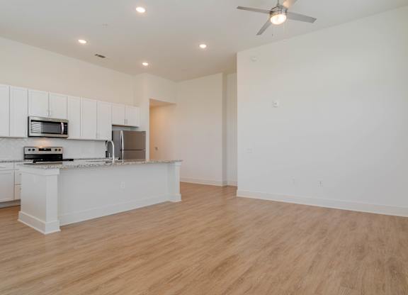 A kitchen with white cabinets and a wooden floor.