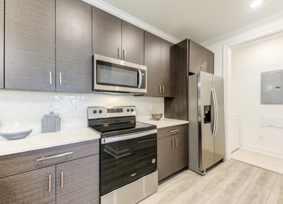 a modern kitchen with stainless steel appliances and dark wood cabinets at Residences at 393 North Apartments, Santa Rosa Beach, FL