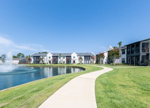a sidewalk next to a lake with apartments in the background at Residences at 393 North Apartments, Santa Rosa Beach
