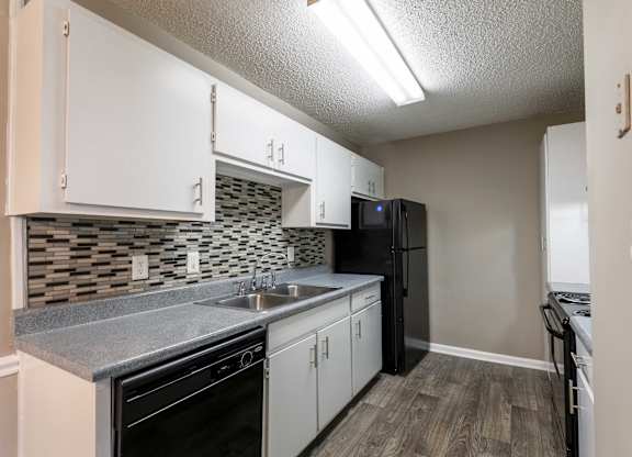 A kitchen with black appliances and white cabinets.
