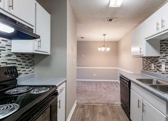 A kitchen with a black stove top oven and white cabinets.