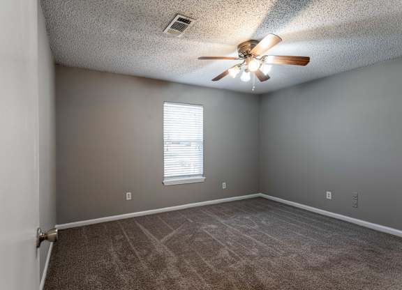 A room with a ceiling fan and a window with blinds.