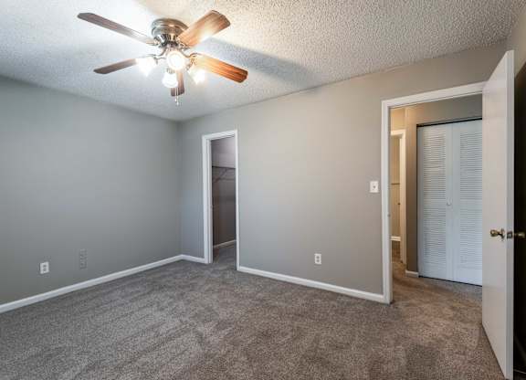 A room with a ceiling fan and carpeted floor.