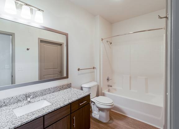 A white toilet sits in a bathroom next to a sink and a bathtub.