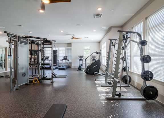 A spacious gym with a variety of equipment including a treadmill, weights, and a bench.