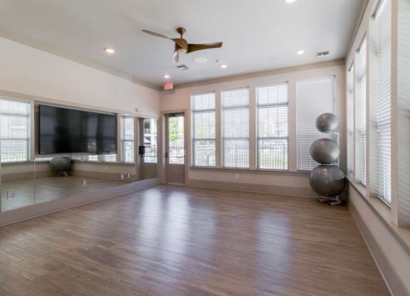 A spacious room with a ceiling fan and large windows.