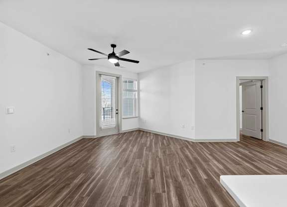 A room with a ceiling fan and wooden flooring.