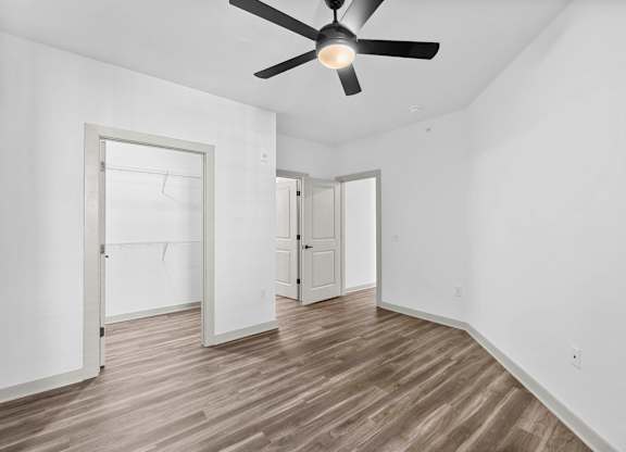A room with a ceiling fan and wooden floors.