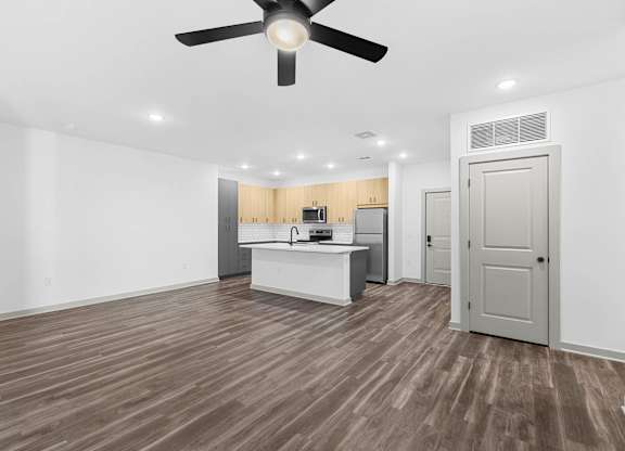 A room with a ceiling fan and wooden flooring.