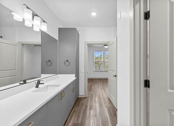 A bathroom with a white counter and a mirror above it.