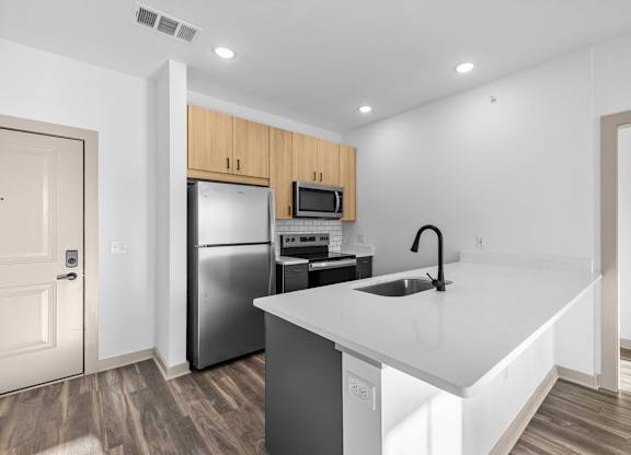 A kitchen with a white counter top and a black faucet.