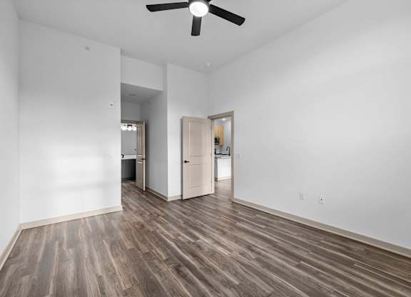 A room with a ceiling fan and wooden flooring.