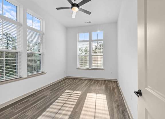 A room with a ceiling fan and wooden flooring.