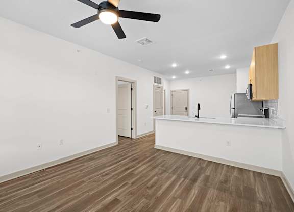 A room with a ceiling fan and wooden flooring.