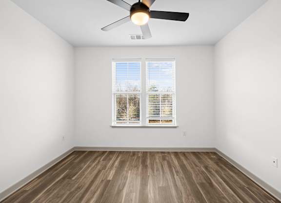 A room with a ceiling fan and a window with blinds.
