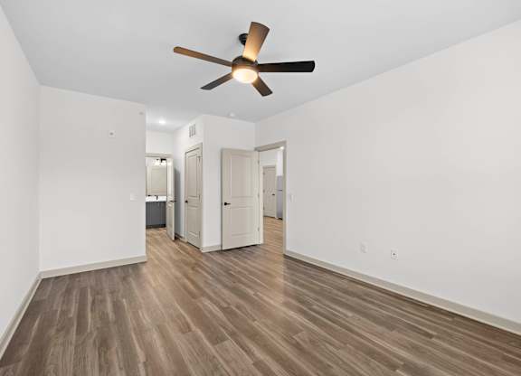 A room with a ceiling fan and wooden flooring.