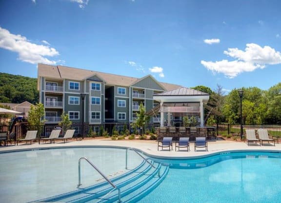 a swimming pool with chairs and a building in the background  at Lullwater at Big Ridge, Hixson, Tennessee