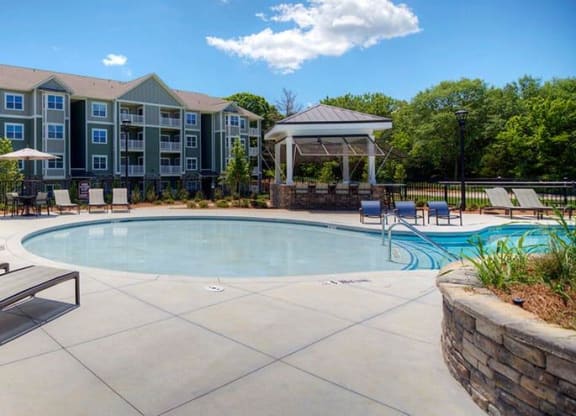 a swimming pool with chairs and a building in the background  at Lullwater at Big Ridge, Hixson, Tennessee