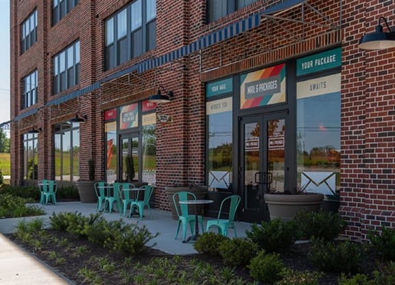 a brick building with green chairs in front of it at Livingston Flats Apartments, Chesterfield, VA