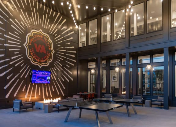 a large open area with ping pong tables and a large illuminated logo on the wall at Livingston Flats Apartments, Virginia,23832