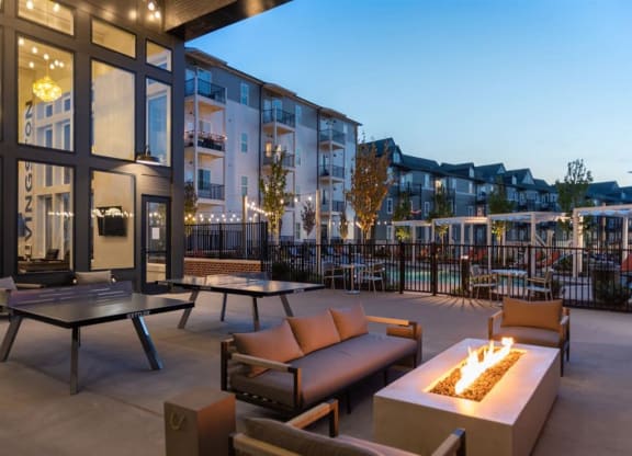a patio with couches and tables and a fire pit in front of an apartment building at Livingston Flats Apartments, Chesterfield, VA, 23832