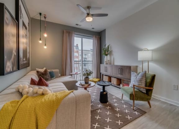 a living room with a ceiling fan and a large window at Flats at West Broad Village, Glen Allen, VA 23060