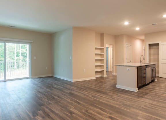 an empty living room with a kitchen and a door leading to a balcony  at Sapphire at Centerpointe, Midlothian, VA