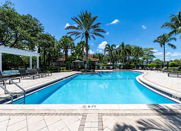 A swimming pool surrounded by palm trees and lounge chairs.