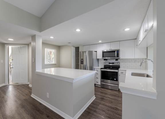A modern kitchen with stainless steel appliances and a breakfast bar.