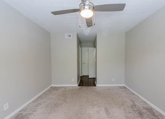 A room with a ceiling fan and carpeted floor.