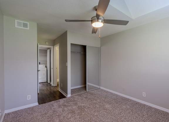 A room with a ceiling fan and carpeted floor.