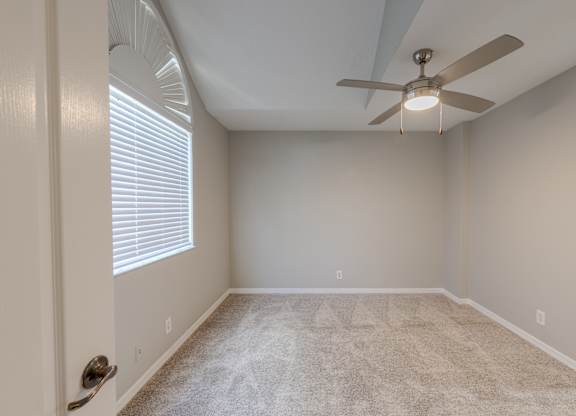 A room with a ceiling fan and carpeted floor.