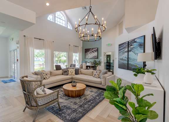 A living room with a large sectional sofa, a coffee table, and a chandelier.