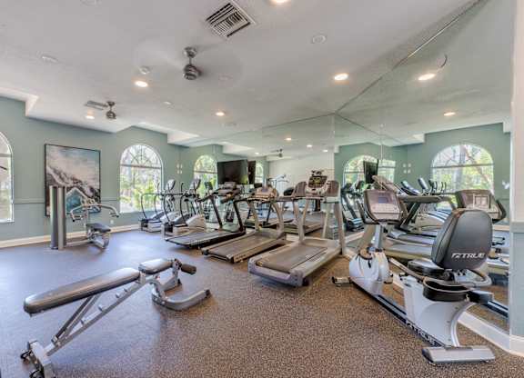 A gym with a variety of equipment including treadmills, weights, and exercise machines.