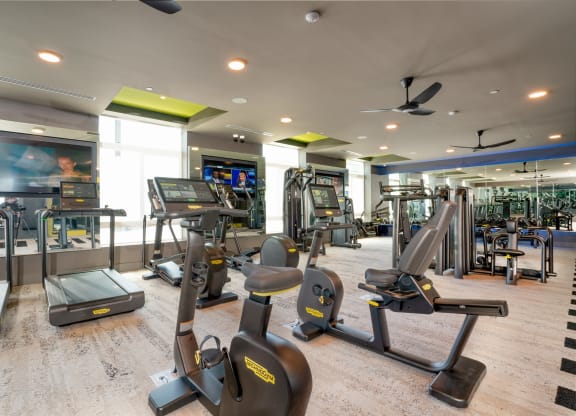 a gym with cardio machines and other exercise equipment in a building with windows at Vista Brooklynn Apartments, Florida, 32202