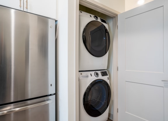 a small laundry room with a washer and dryer and a stainless steel refrigerator at Vista Brooklynn Apartments, Jacksonville