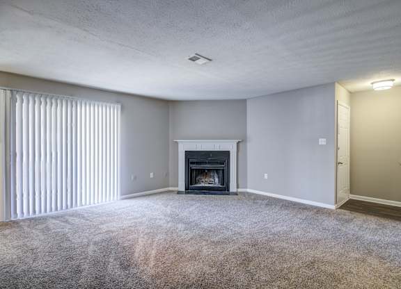 A living room with a fireplace and carpeted floor.