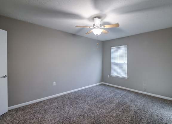 A room with a ceiling fan and carpeted floor.
