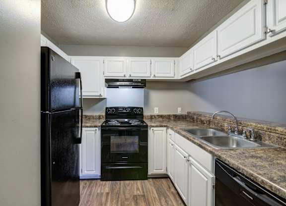 A kitchen with a black refrigerator, stove, and oven.