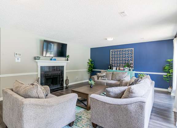 A living room with a fireplace and two grey chairs.