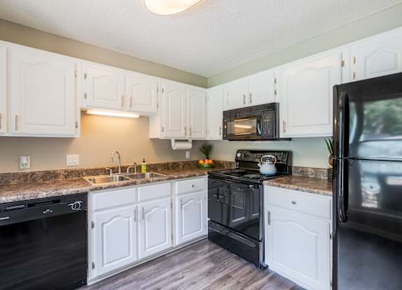 A kitchen with white cabinets and black appliances.