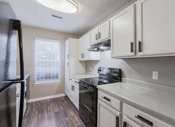 A kitchen with white cabinets and a black fridge.