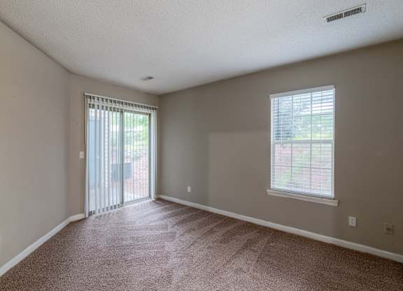 A room with a carpeted floor and a window with blinds.