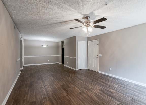 A room with a ceiling fan and wooden flooring.