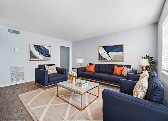 A living room with a blue couch, a coffee table, and two framed pictures on the wall.