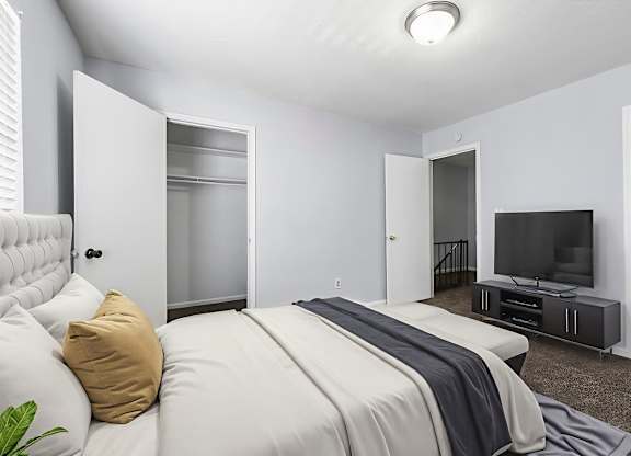 A bedroom with a bed, a television, and a window with blinds.