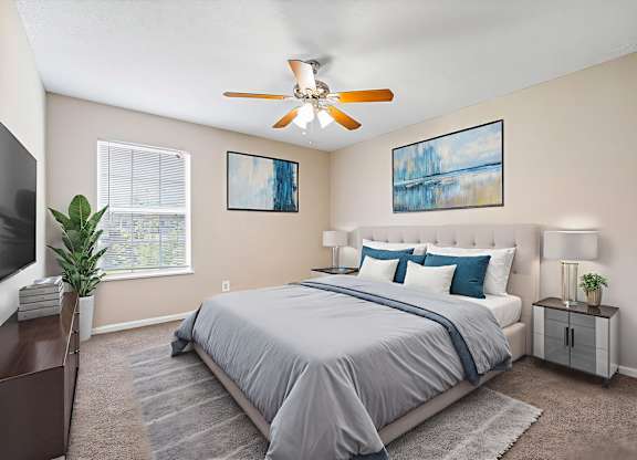 A bedroom with a large bed and a ceiling fan.