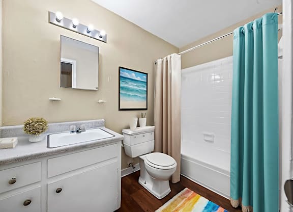 A bathroom with a white toilet, sink, and a white cabinet with drawers.