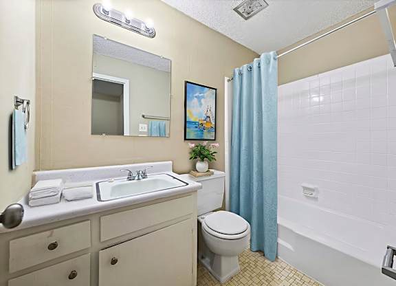 A bathroom with a toilet, sink, and shower.