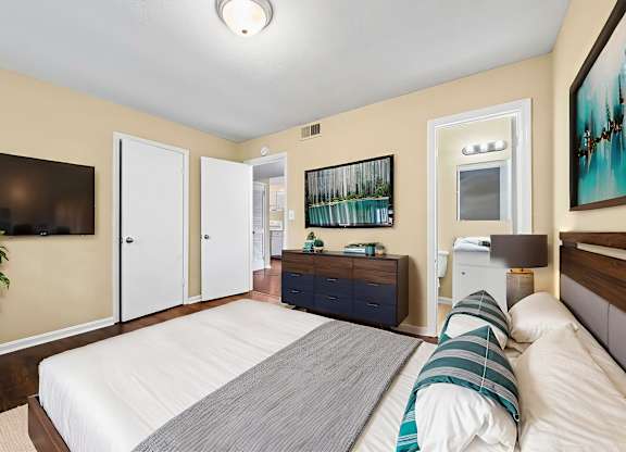 A bedroom with a large bed and a TV on the wall.